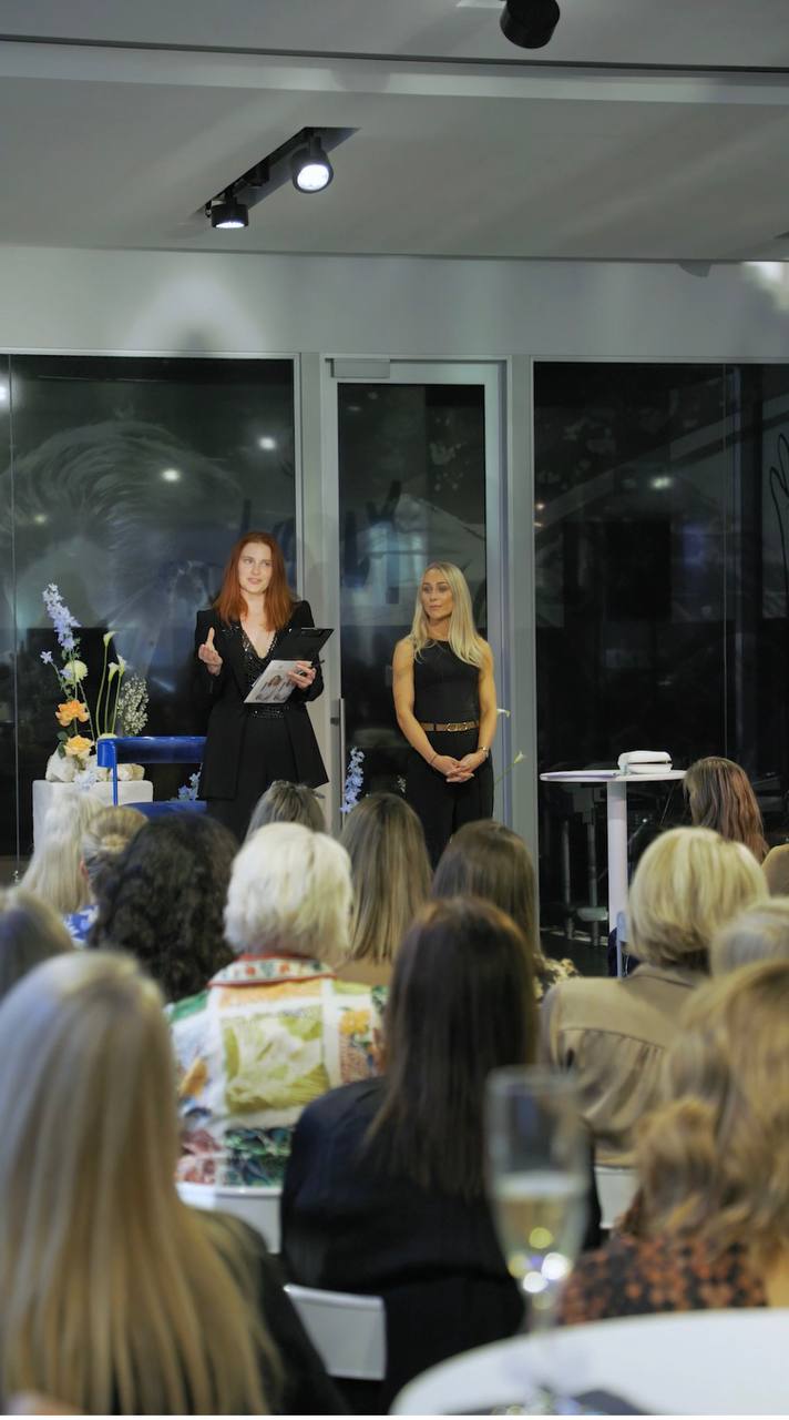Dasha speaking on stage to an audience